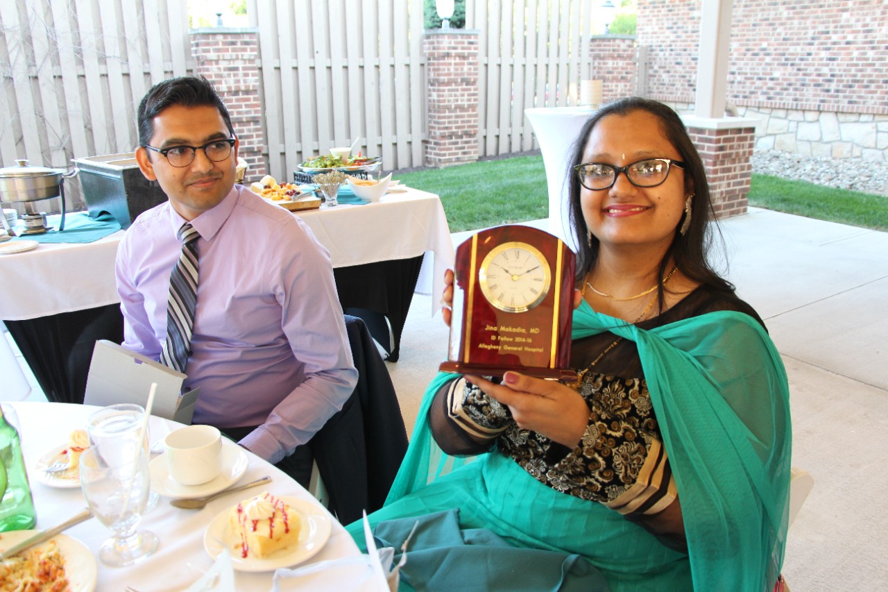 2015-2016 graduate Jina Makadia, MD holding a graduation gift at a dinner party.