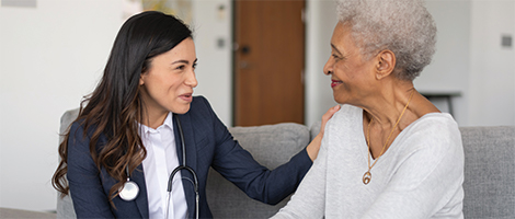 AHN doctor sitting on a couch providing customer service to a patient.