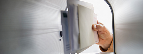 A view from the inside of a mailbox as a hand pulls mail out of it, away from the camera.