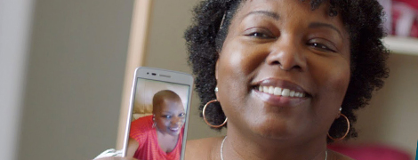 A woman sharing a photo on her mobile phone of her during treatment.