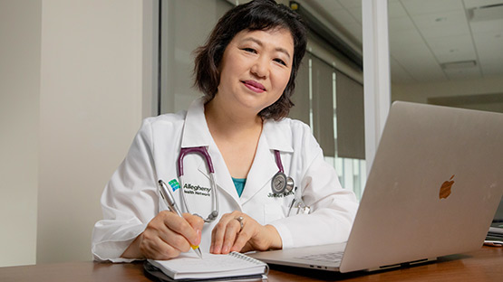 A doctor taking notes in a notebook during a video visit.