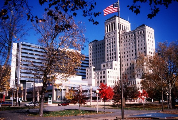 Allegheny General Hospital stands tall with an American flag, surrounded by autumn trees.