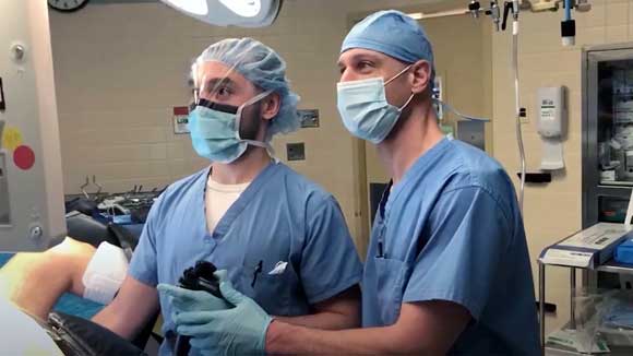 Two surgeons working together on an endocscopic procedure of the colon.