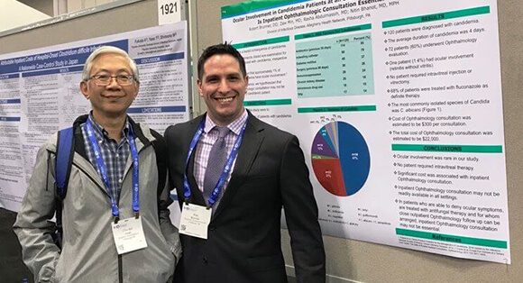 Two medical professionals standing in front of research display