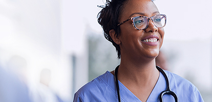 A doctor with a stethoscope around her neck is smiling as she begins her residency with AHN.