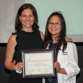 A resident and her mentor holding up a diploma that they won.