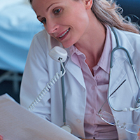 A doctor on the phone while looking at a chart.