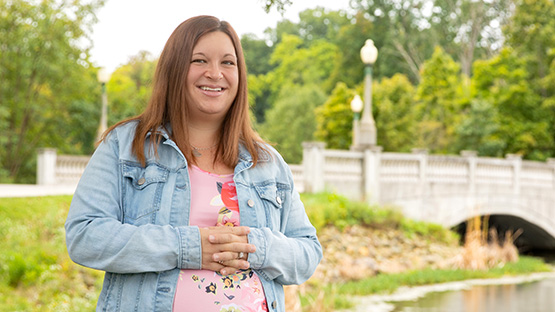 AHN Grove City patient Kayla Gregorish standing by a body of water and a bridge smiling into the camera.