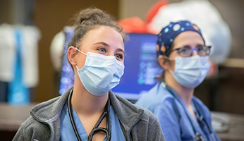 Two AHN West Penn Hospital nurses wearing masks while sitting at a nurse's station.