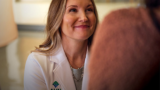 A doctor in a lab coat looking up smiling at a patient