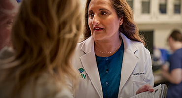 A doctor in a lab coat talking to patients