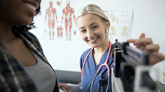 A nurse weighing a patient on a scale.