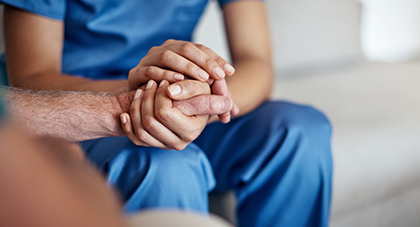 A doctor holding hands and comforting a patient.