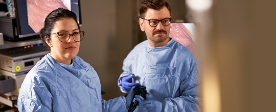 A medical professional in a white coat talks to two other people in a meeting room.