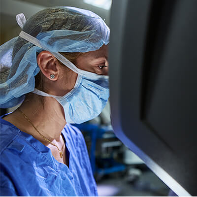 A doctor in scrubs looking at a monitor in an operating room 