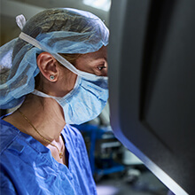 A doctor in scrubs looking at a monitor in an operating room 