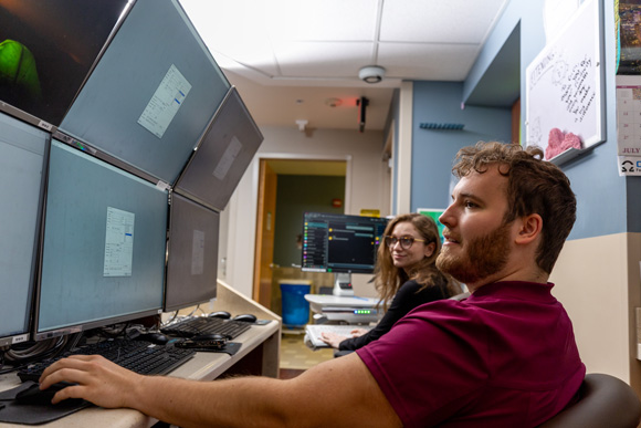 Two medical professionals are closely monitoring patient information from a nurse's station at the epilepsy monitoring unit.