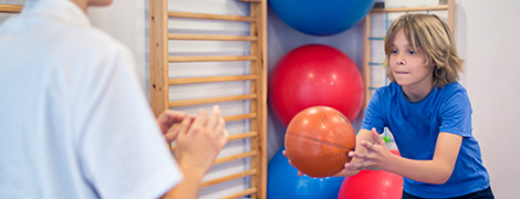 image of young boy throwing a medicine ball during physical therapy appointment