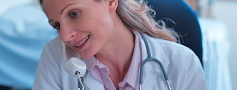 A doctor on a phone while looking at papers in her hand.