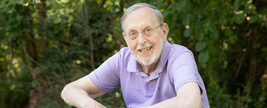 AHN patient Carleton Weber smiling while looking into the camera as he is sitting outside on a bench.